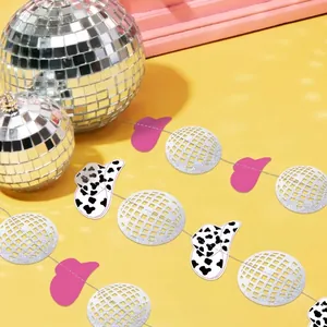 Détail de la guirlande de boules disco et chapeaux de cowboy imprimé vache sur fond jaune.