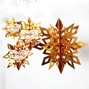 Detailed view of several golden 3D paper snowflake hanging ornaments with a mirror finish