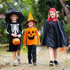 Bambini con accessori per feste di Halloween e sacchetti regalo in un giardino all'aperto