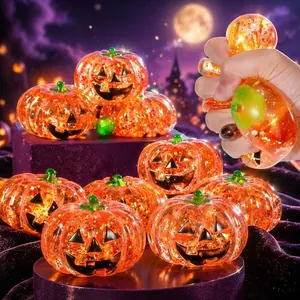 Primer plano de una mano apretando un juguete de calabaza de Halloween translúcido