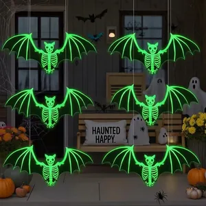 Macro view of six glowing green skeleton bat hanging decorations in a dark porch setting.