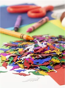 Colorful dinosaur confetti pieces for Jurassic themed birthday party table decoration