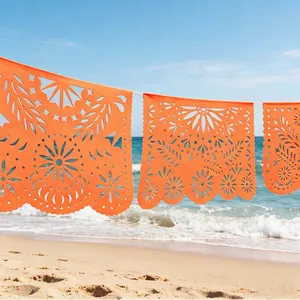 Ζωντανό πορτοκαλί μεξικάνικο banner Papel Picado κρεμασμένο σε μια ηλιόλουστη παραλία.