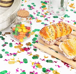 Hawaii beach theme party confetti with colorful flamingo and pineapple shapes on a table