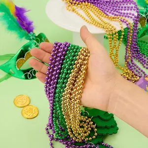 Gros plan de colliers de perles Mardi Gras brillants violet vert et or dans la main
