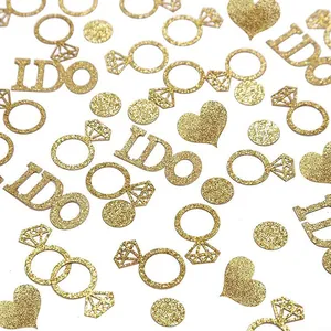 Close-up detail of golden glitter I DO, ring, and heart-shaped confetti for wedding parties