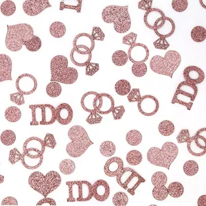 Close-up of rose gold glitter confetti with hearts, rings, and 'I DO' text