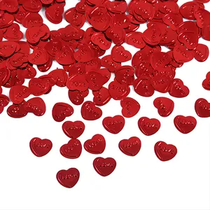 Makro-Detail von rotem Herz-Konfetti mit geprägten LOVE-Buchstaben für die Hochzeitsdeko