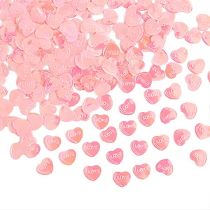 Detailansicht rosa herzförmiger Konfetti-Pailletten mit geprägtem LOVE-Schriftzug