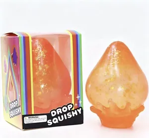 Gros plan d'un jouet spongieux orange pailleté avec sa boîte d'emballage arc-en-ciel