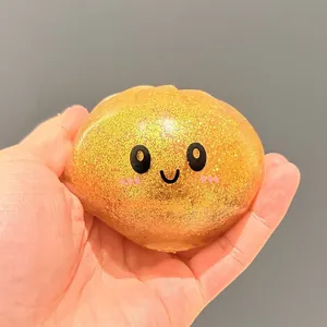 Gros plan d'un jouet squishy en forme de brioche dorée pailletée avec un visage souriant mignon
