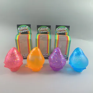 Primer plano de cuatro juguetes squishy de gota de agua con purpurina y cajas arcoíris