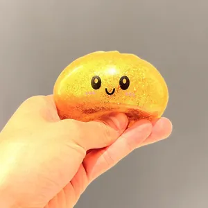 Gros plan d'une main pressant un jouet squishy doré à paillettes pour le stress.