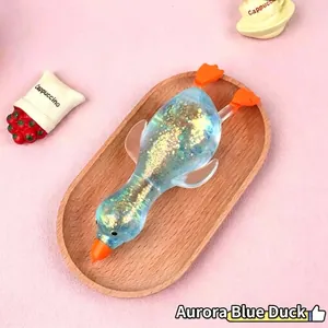 Close-up of translucent aurora blue glitter squishy duck toy on a wooden tray detail