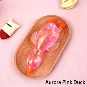 Detail view of a pink glitter duck squishy toy on a wooden tray for stress relief.