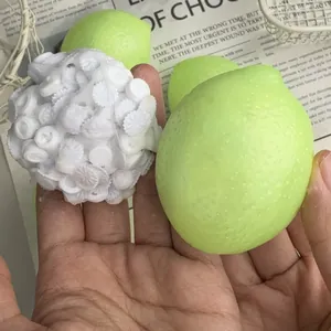 Close-up detail of green lemon squeeze toy and textured white stress ball held in hand.