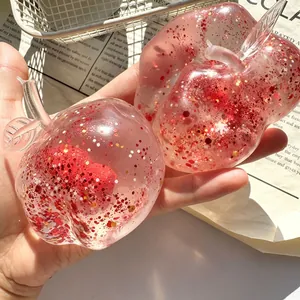Close-up of apple squishy toy with red glitter inside, held in hand for stress relief.