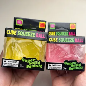 Gros plan sur les balles de stress Cube Squeeze Ball jaunes et roses dans leur boîte