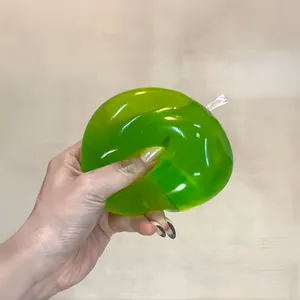 Detailansicht des elastischen Zusammendrückens eines grünen Apfel-Stressspielzeugs