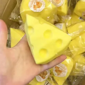 Macro view of a hand squeezing a soft yellow triangular cheese squishy stress toy detail