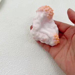 Close-up of milky white handmade squishy toy held in hand showing bumpy texture