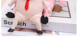 Detalle de juguete antiestrés con forma de cerdo rosa y una pequeña corbata roja decorativa