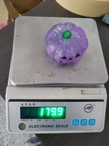 Purple glittery Halloween pumpkin squishie toy weighing 179.9g on a digital scale