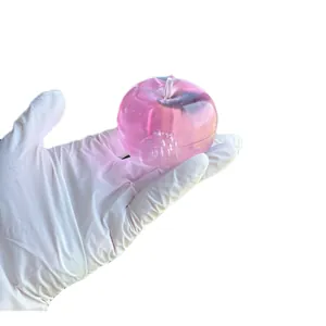 Detailed view of a pink translucent apple shaped squishy stress relief toy in hand
