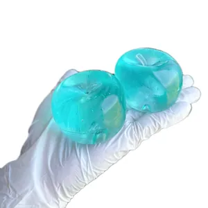 Close-up of translucent teal apple-shaped squishy squeeze toys held in a gloved hand