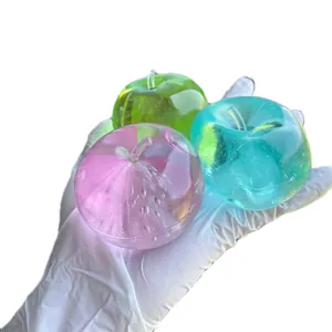Three colorful translucent apple-shaped squishy stress relief toys held in a hand.