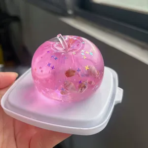 Pink transparent apple squishy toy filled with glitter stars and real seashells