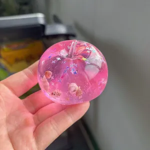 Macro detail of a pink transparent apple squishy toy containing shells and sparkling glitter stars