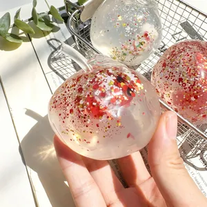 Close-up detail of a transparent apple squishy toy filled with red and gold glitter