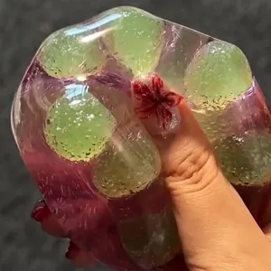 Macro view of a grape-shaped translucent purple and green squishy stress relief toy