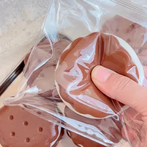 Detail einer Hand, die ein realistisches Schokoladenkeks-Quetschspielzeug zum Stressabbau drückt