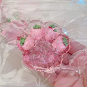 Close-up of pink strawberry cat paw squishy toy with glitter and charms in plastic bag