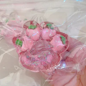 Close-up of a pink strawberry cat paw squishy stress relief toy with sparkling glitter
