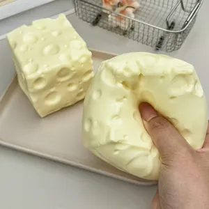 Gros plan d'une main pressant un jouet squishy en forme de fromage, texture souple.