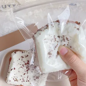 Nahaufnahme einer Hand, die ein weiches Erdbeer-Toast-Squishy-Spielzeug in einem Plastikbeutel drückt