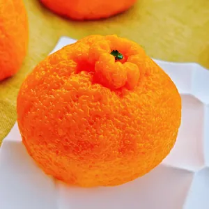 Juguete antiestrés realista con forma de naranja Dekopon en un plato blanco