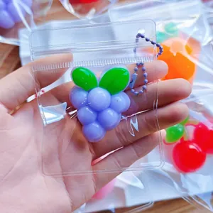 Detalle de un juguete antiestrés de TPR con forma de uva morada en una mini bolsa clara