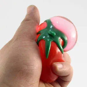 Primer plano de una mano apretando un juguete antiestrés con forma de tomate