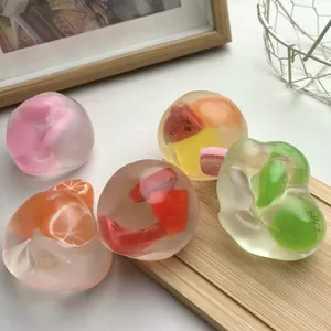 Gros plan de balles anti-stress translucides aux fruits sur un support en bois.