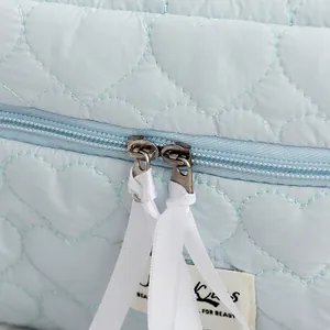 Detalle de neceser acolchado con corazones, doble cremallera y cintas blancas