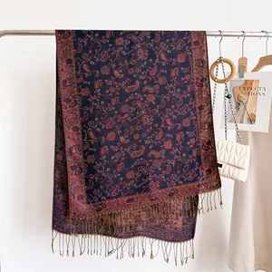 Close-up of a vintage paisley pattern long scarf with tassels hanging on a garment rack.