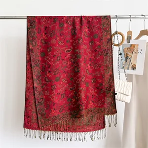 Elegant red paisley scarf with fringe tassels shown in a stylish fashion display