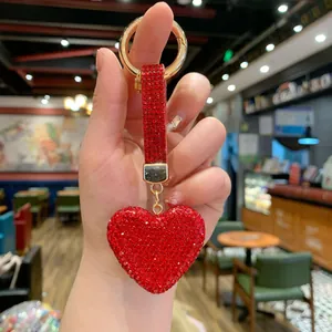 Detail of red heart keychain with shiny rhinestones and gold ring bag pendant.