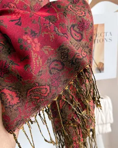 Detailed close-up of a red and black paisley pattern scarf with elegant tassel fringe