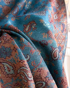 Close-up detail of soft paisley pattern jacquard fabric scarf with teal and orange hues