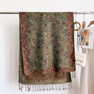 Close-up of elegant green pashmina scarf with vintage paisley patterns and soft tassels